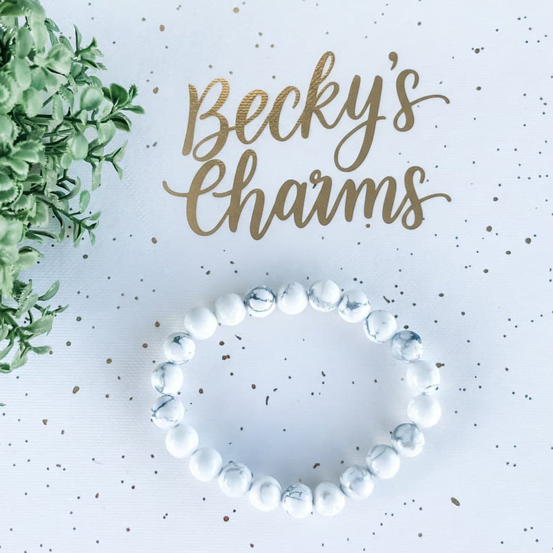 White and blue marbled gemstone bracelet for spiritual healing and chakra balance, styled with greenery and gold text