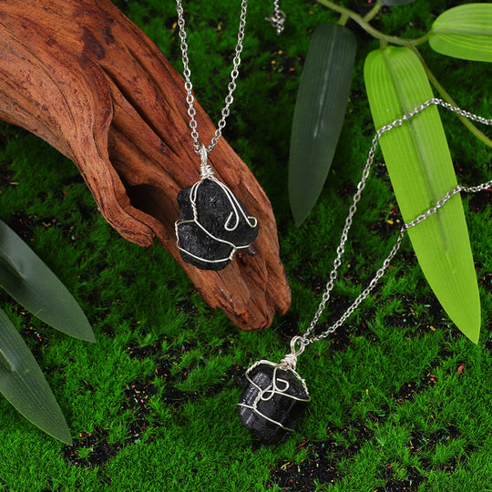 Handmade black crystal pendant necklaces with silver wire wrap, set on moss and wood for natural healing energy.
