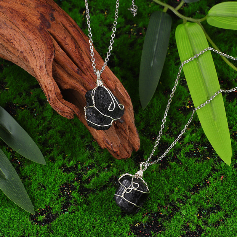 Handmade black crystal pendant necklaces with silver wire wrap, set on moss and wood for natural healing energy.