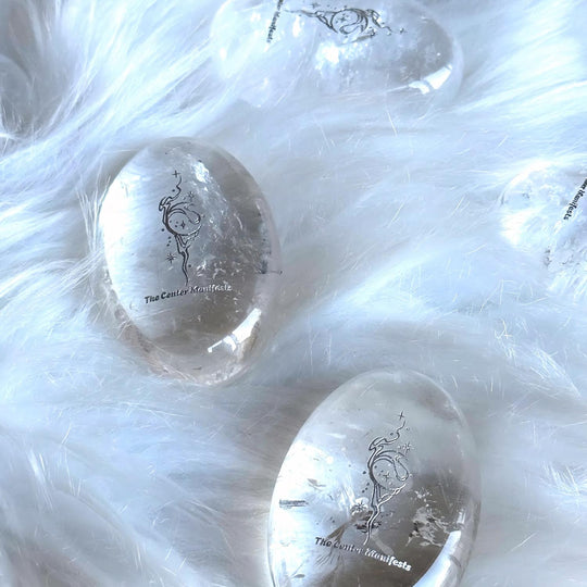 Clear quartz crystal eggs with engraved designs on soft white fur, ideal for spiritual healing and chakra balance.