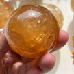 Hand holding a polished citrine crystal sphere for healing and spiritual growth