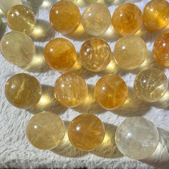 Polished citrine spheres for healing, chakra balance, and spiritual growth, displayed on soft white fabric.