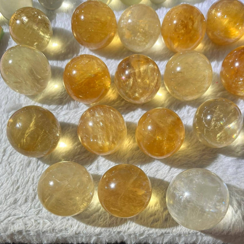 Polished citrine spheres for healing, chakra balance, and spiritual growth, displayed on soft white fabric.