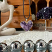 Heart-shaped amethyst crystal pendant necklace for love and spiritual healing, displayed with healing stones