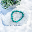Malachite beaded bracelet on crystal cluster with green floral accents, ideal for healing and spiritual growth