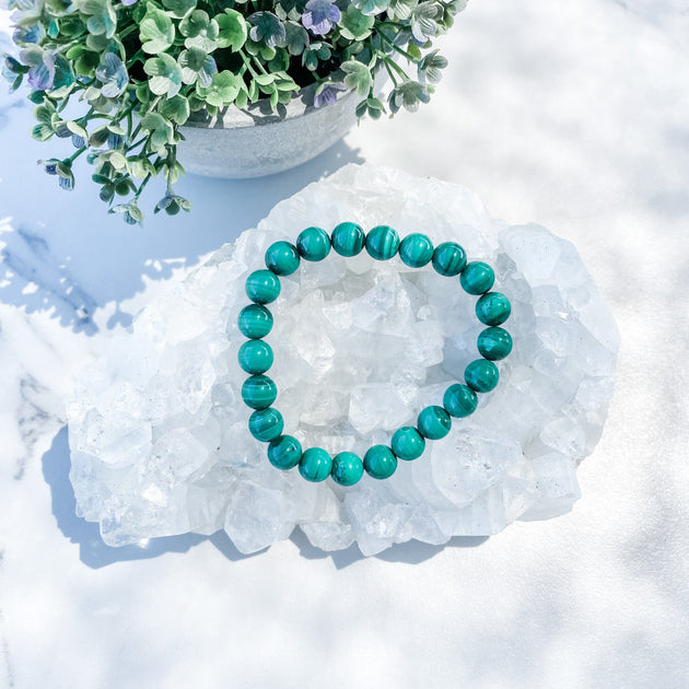 Malachite beaded bracelet on crystal cluster with green floral accents, ideal for healing and spiritual growth