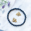 Black gemstone bracelet with gold bee charms, lavender sprigs on marble, healing crystal jewelry