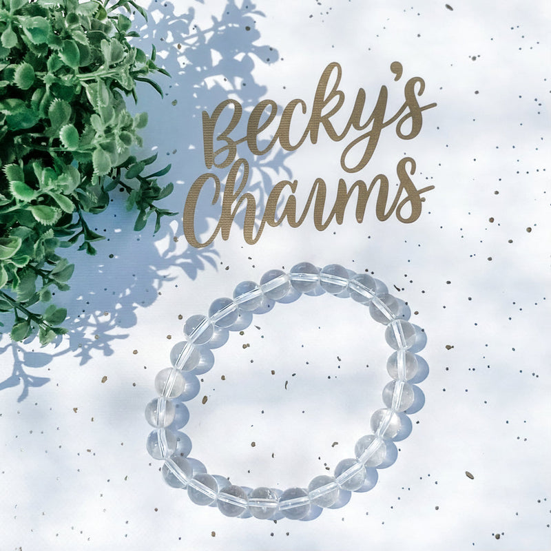 Clear crystal bracelet for spiritual growth and anxiety relief, with greenery and Becky's Charms logo