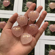 Hand holding pink heart-shaped rose quartz crystals engraved with 777 make a wish, spiritual healing stones