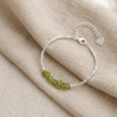 Silver bracelet with green beads on beige fabric