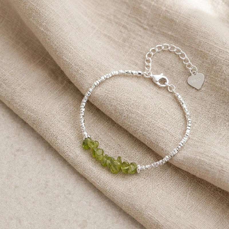 Silver bracelet with green beads on beige fabric