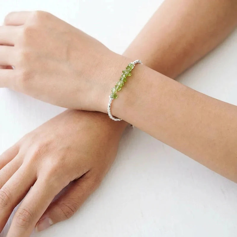 Person wearing a bracelet with green beads on a white background