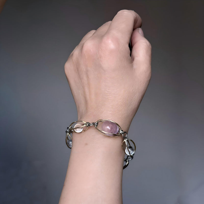 Hand wearing handmade gemstone bracelet with pink and clear crystals for love and healing