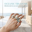 Hand wearing oceanic treasure rings with seashells and blue gemstones, perfect for seaside style