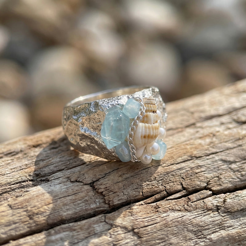 Handmade silver ring with aquamarine crystals, seashells, and pearls on driftwood, perfect for spiritual jewelry lovers.