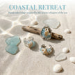 Handcrafted sea-inspired rings with seashells, pearls, and blue stones on driftwood and sea glass