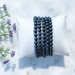 Black onyx beaded bracelets for protection and grounding, displayed on white pillow with lavender