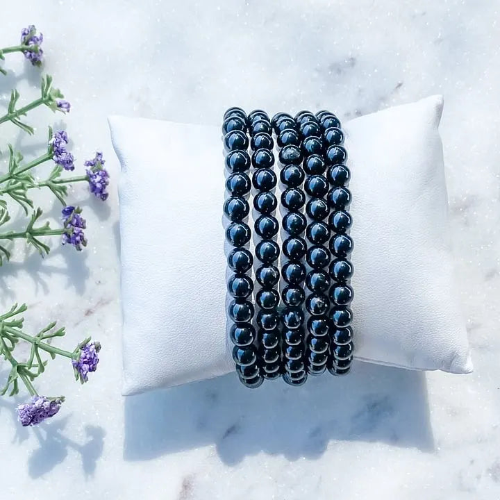Black onyx beaded bracelets for protection and grounding, displayed on white pillow with lavender