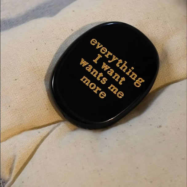 Black obsidian stone with gold inscription 'everything I want wants me more' for spiritual growth and manifestation