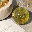 Golden citrine crystal sphere for healing and spiritual growth, with dried flowers and stone bowl
