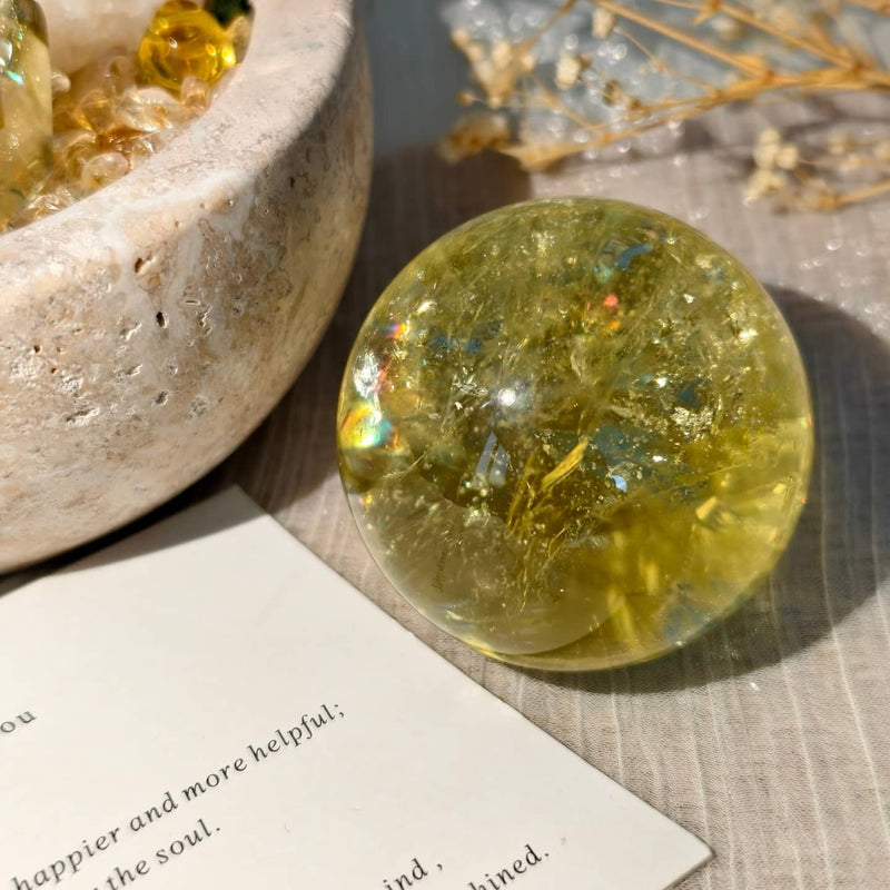 Golden citrine crystal sphere for healing and spiritual growth, with dried flowers and stone bowl