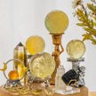 Yellow citrine crystal spheres, points, and healing stones on ornate stands for spiritual energy and chakra balance