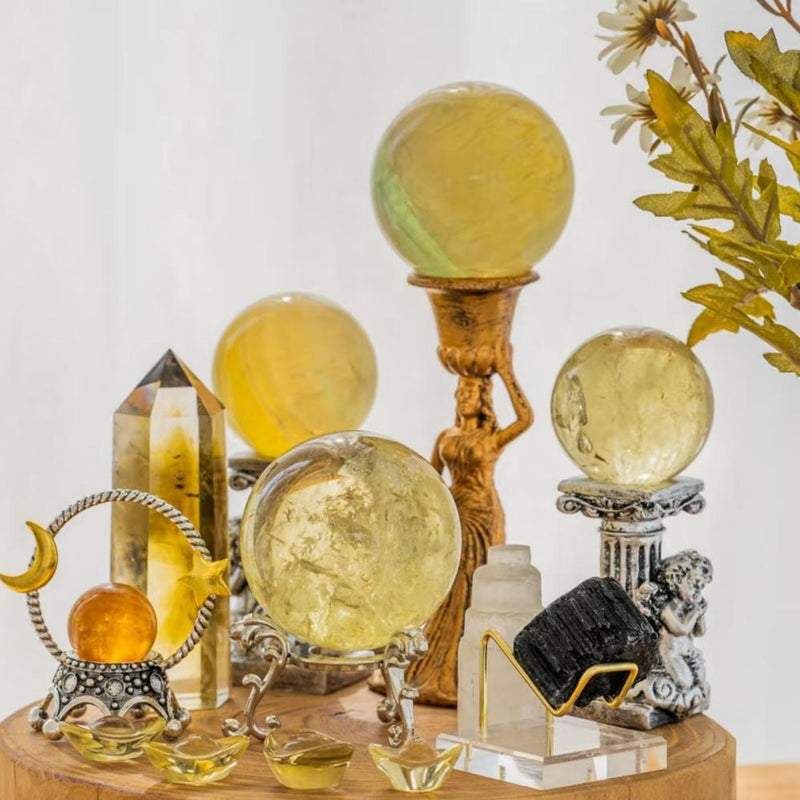 Yellow citrine crystal spheres, points, and healing stones on ornate stands for spiritual energy and chakra balance