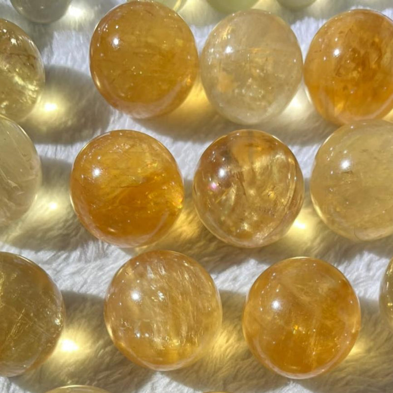 Polished citrine crystal spheres for healing, chakra balance, and spiritual growth on soft white surface