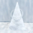 Clear quartz crystal bracelet on white marble pyramid, ideal for spiritual healing and chakra balance
