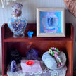 Amethyst crystal decor with angel art, healing stones, and candle on wooden shelf for spiritual ambiance