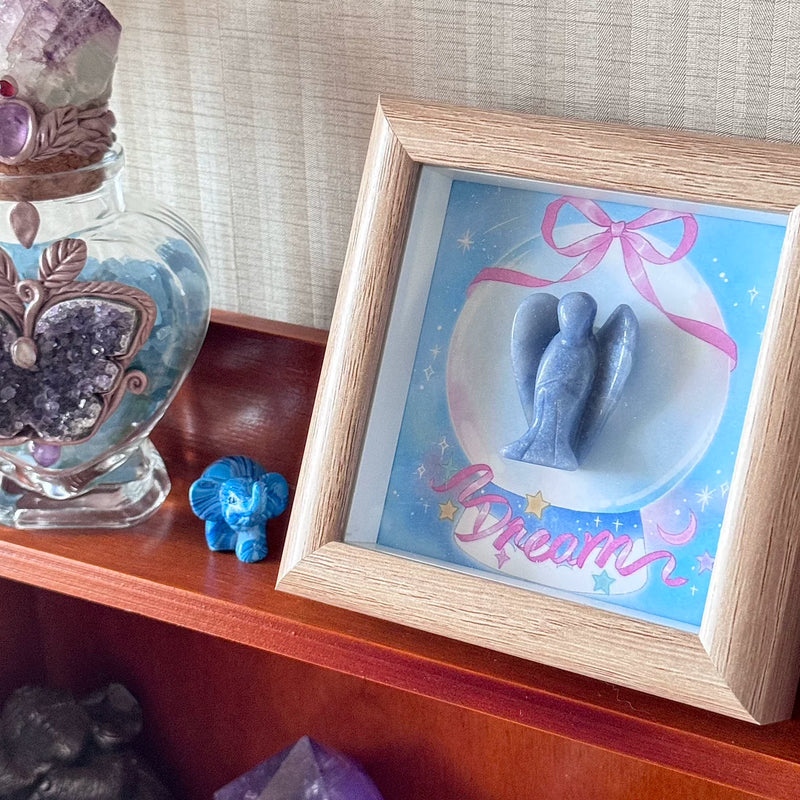 Blue angel crystal art in wooden frame with 'Dream' text, surrounded by healing stones and amethyst decor