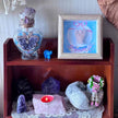 Amethyst crystal decor, angel art, and healing stones on wooden shelf for spiritual space