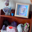 Crystal healing display with amethyst, rose quartz, angel art, and candle for spiritual wellness and protection