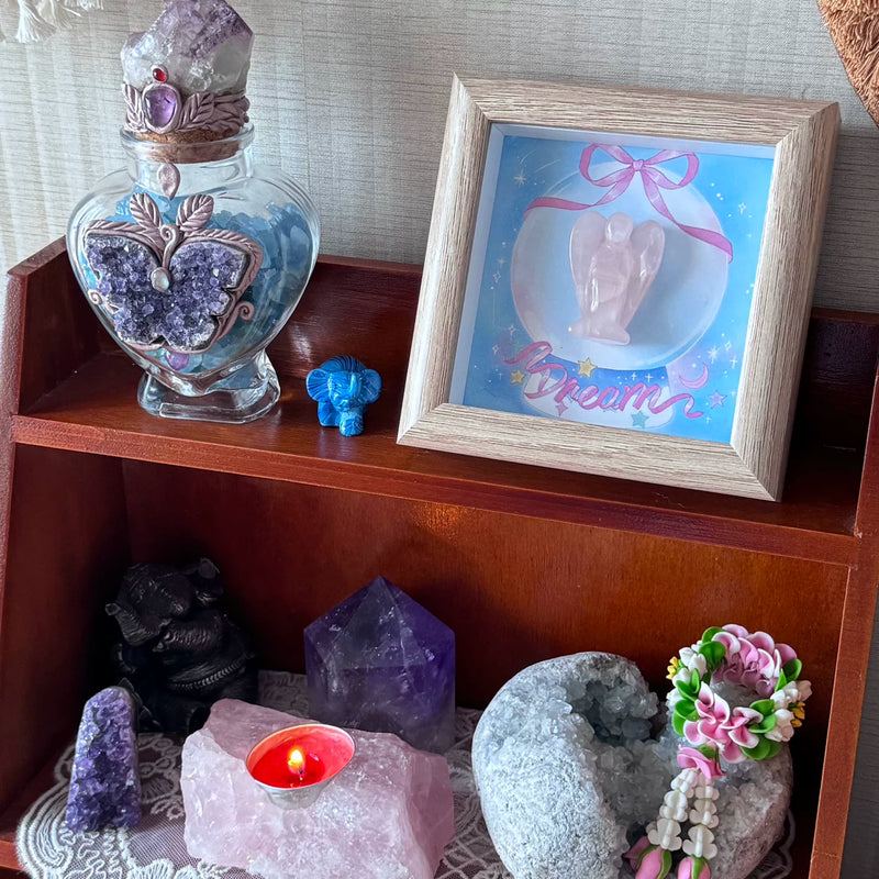 Crystal healing display with amethyst, rose quartz, angel art, and candle for spiritual wellness and protection