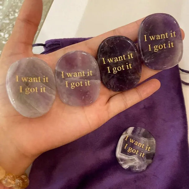 Hand holding engraved amethyst and agate affirmation stones with 'I want it I got it' for manifestation and spiritual growth