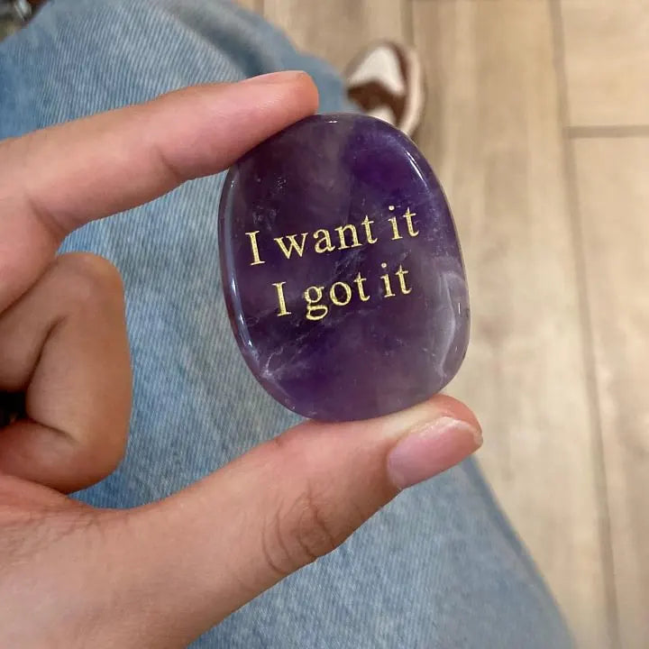 Amethyst crystal stone with 'I want it I got it' engraving, held in hand for manifestation and spiritual growth.