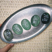 Green engraved healing crystals with 'I am rooted But I flow' on metal tray, spiritual growth stones