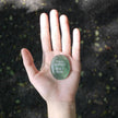 Hand holding green engraved crystal stone with 'I am rooted But I flow' for spiritual grounding and anxiety relief