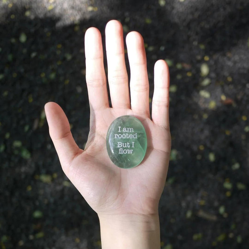 Hand holding green engraved crystal stone with 'I am rooted But I flow' for spiritual grounding and anxiety relief
