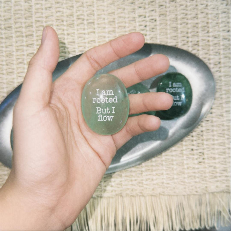 Hand holding green engraved crystal stone with 'I am rooted But I flow' for spiritual growth and anxiety relief