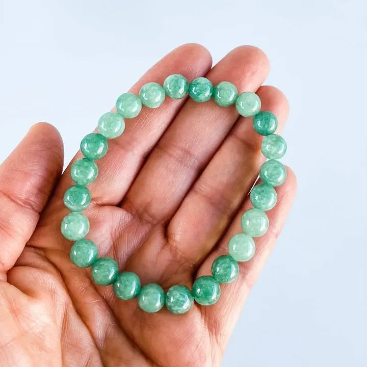 Hand holding green aventurine bracelet for healing and chakra balance, natural gemstone jewelry