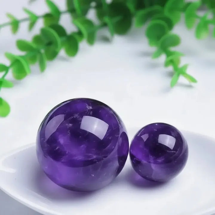 Polished amethyst crystal spheres for spiritual healing and chakra balance, displayed with greenery