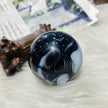 Polished black and white agate sphere for spiritual healing and chakra balance, displayed on soft white surface.