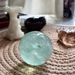 Smooth aquamarine crystal sphere for spiritual healing and chakra balance on woven mat