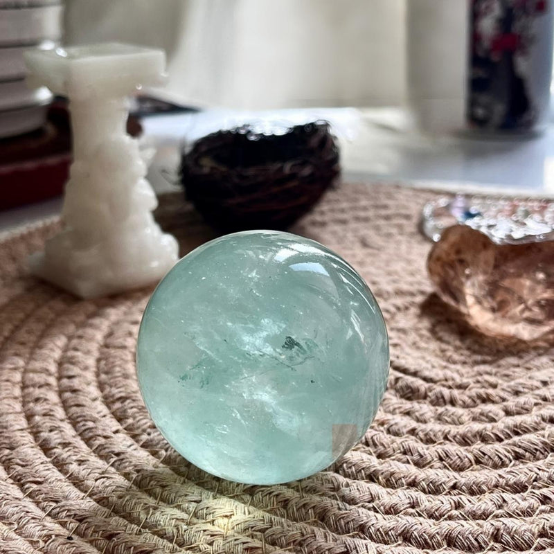 Smooth aquamarine crystal sphere for spiritual healing and chakra balance on woven mat