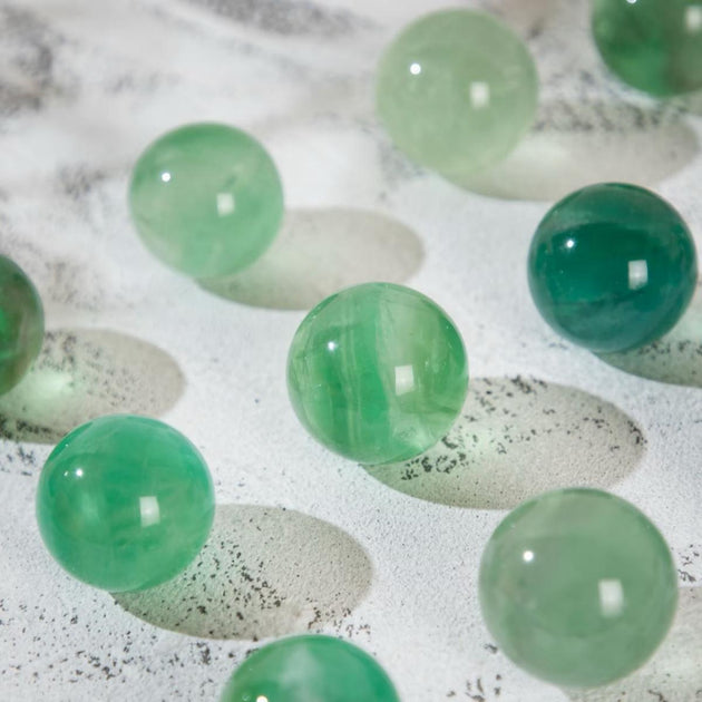 Smooth green crystal spheres for healing and chakra balance on textured surface