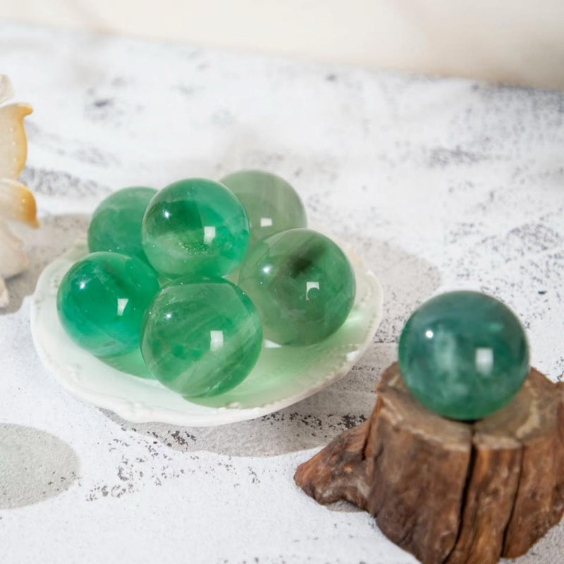 Polished green aventurine spheres for healing, chakra balance, and spiritual growth on rustic wood and ceramic dish