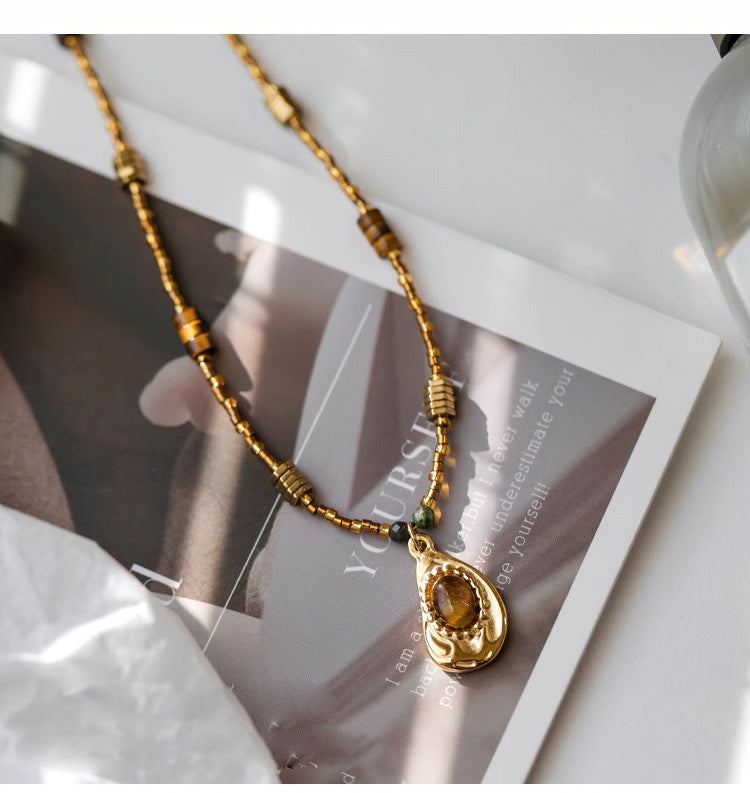 Gold beaded necklace with amber crystal pendant, handmade gemstone jewelry for spiritual healing and protection.