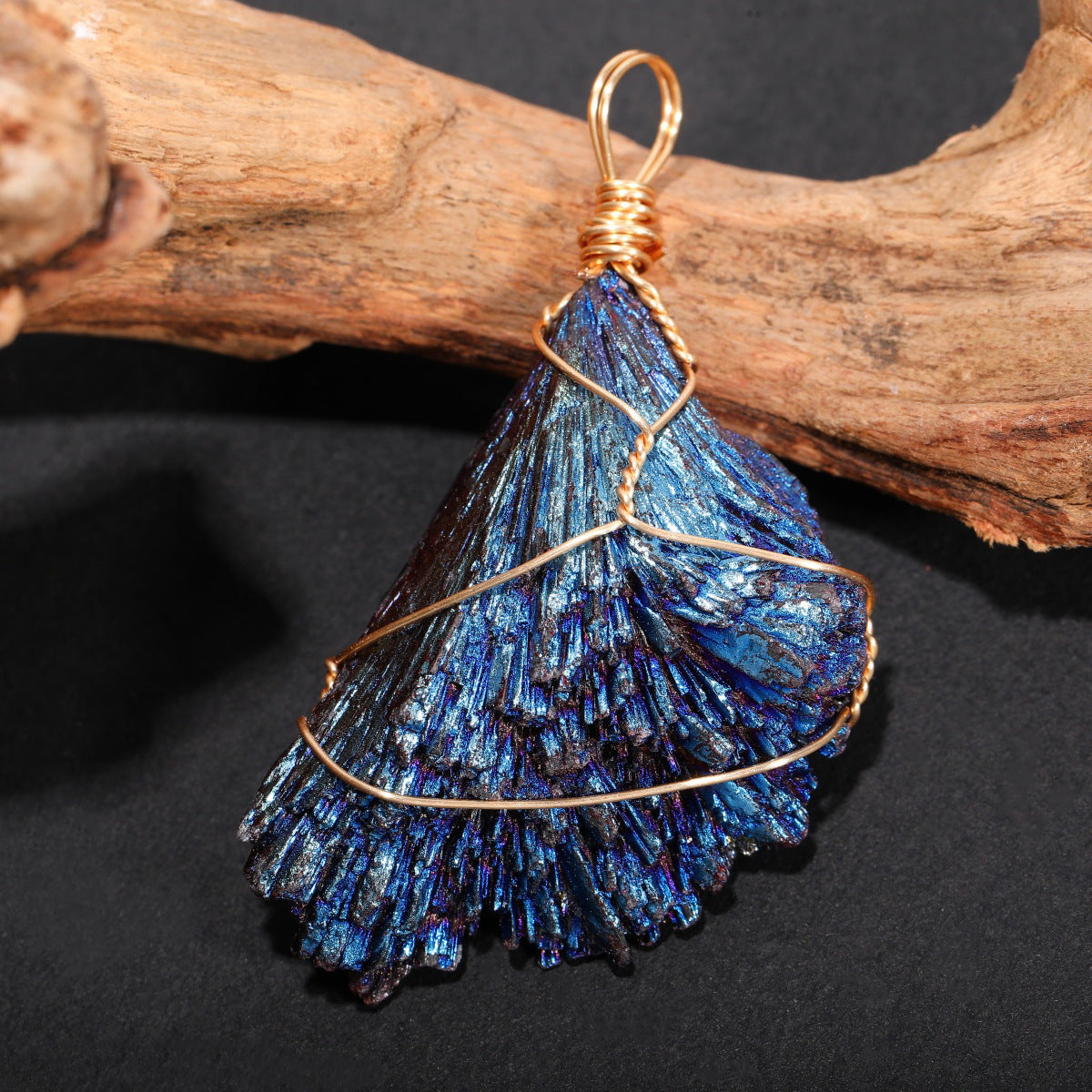 Iridescent blue crystal pendant with gold wire wrapping, natural driftwood background