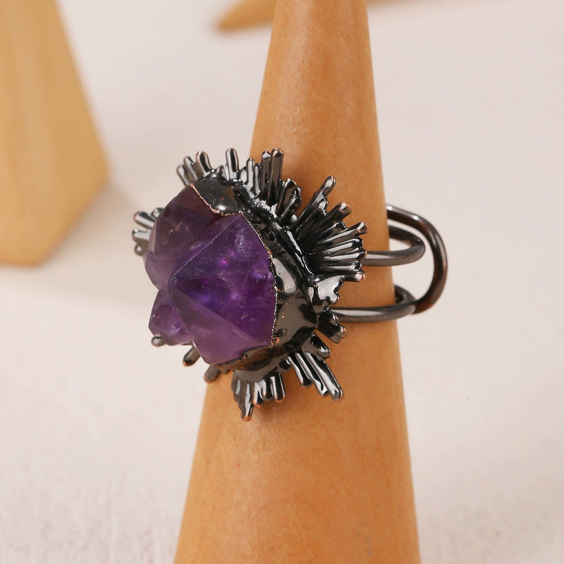 Amethyst crystal ring with black spiky setting on wooden display, handmade gemstone jewelry for spiritual healing